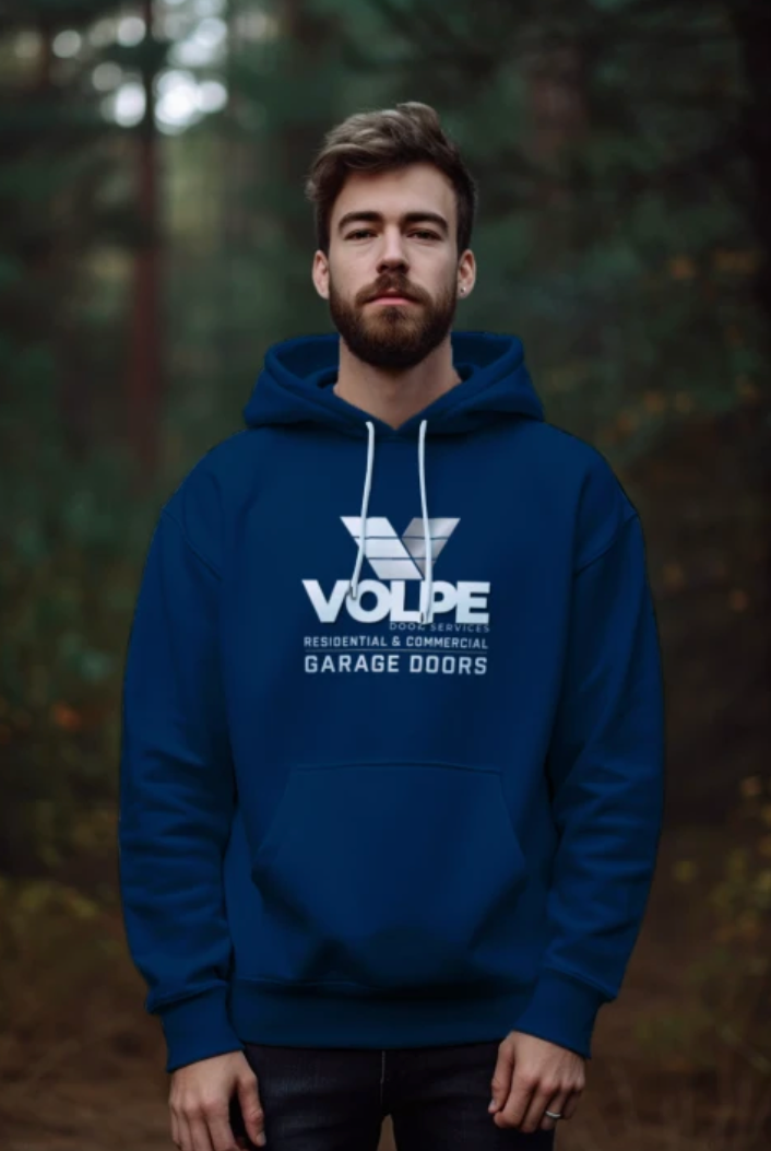 A man wearing a royal blue hoodie with a white printed 'VOLPE GARAGE DOORS' logo stands in a blurred forest setting.