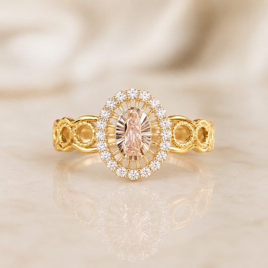 A yellow gold ring with an oval halo of small clear stones and a central marquise-cut peach-pink gemstone, displayed on a light beige reflective surface.