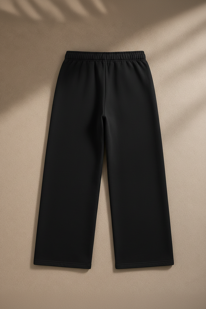 Black wide-leg cropped pants with an elastic waistband, laid flat on a beige background with soft leaf shadows.