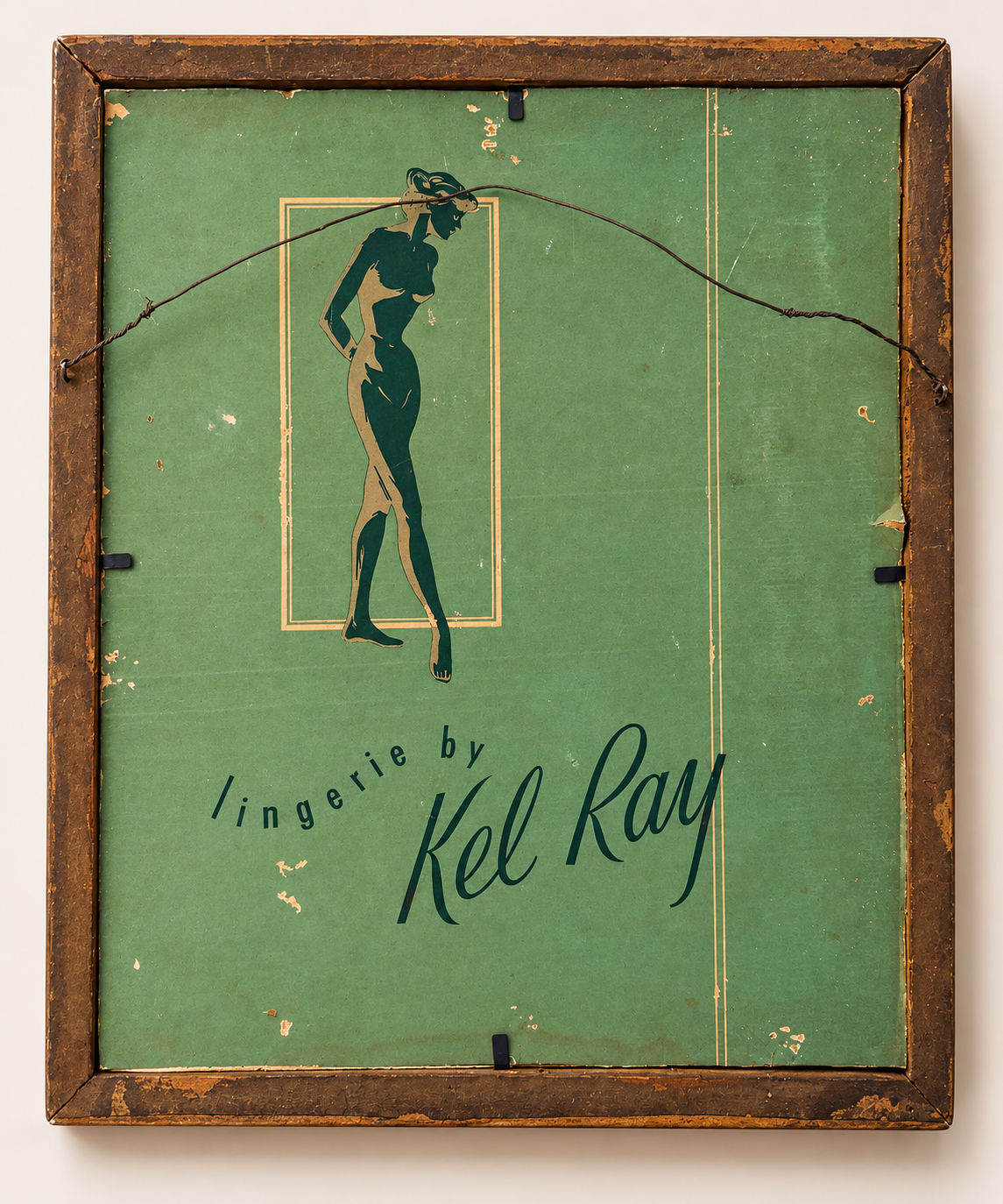 Vintage Kel Ray lingerie advertising sign or plaque with a green background, a dark green female silhouette figure, and distressed brown wooden frame.